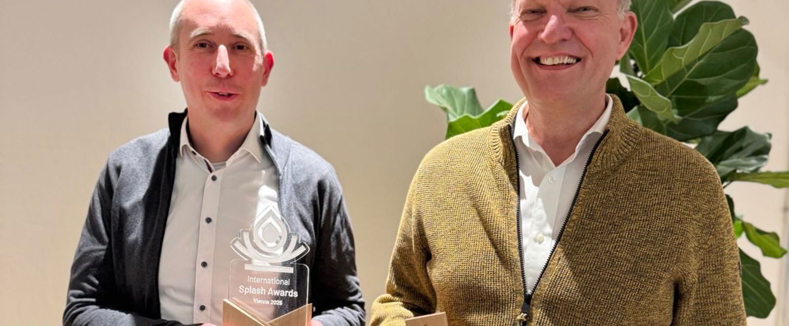 Zwei als Männer lesbare Personen mit Trophäen in der Hand.