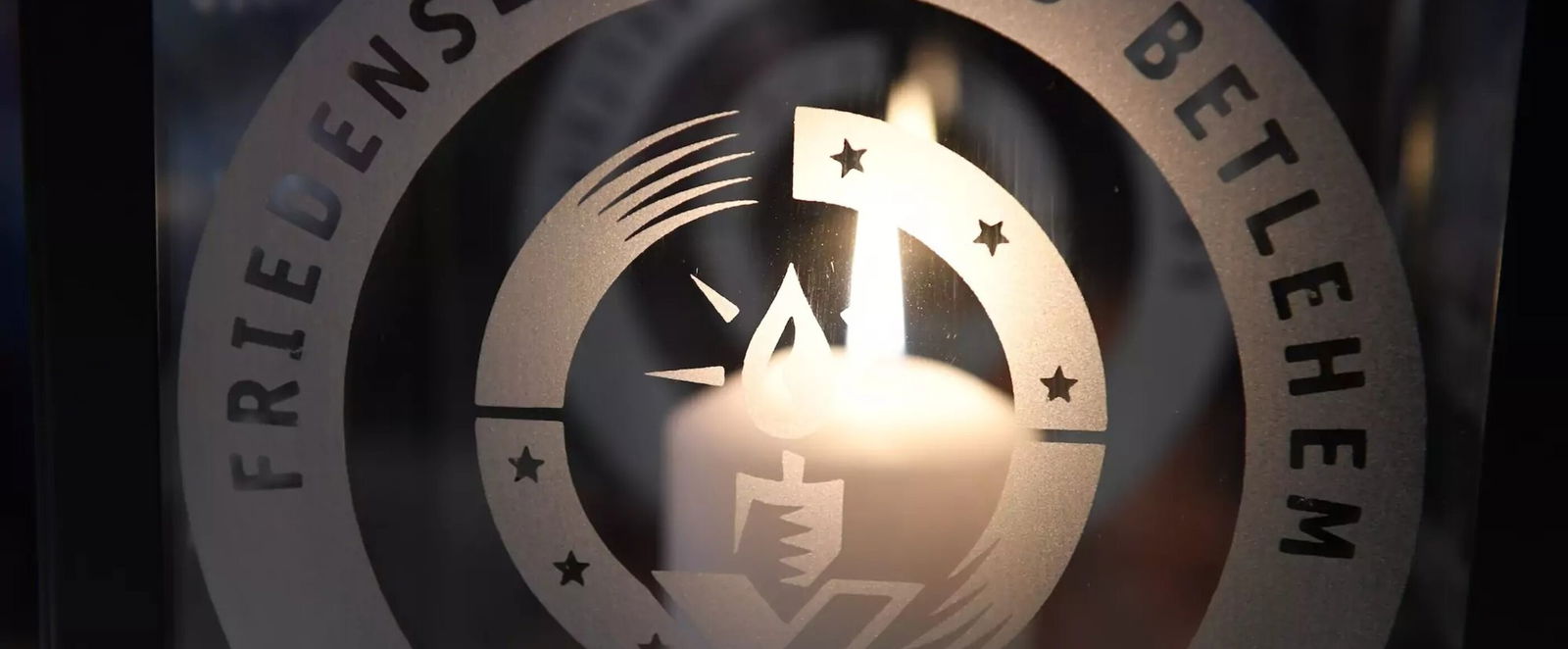Eine Kerze hinter einem Logo mit der Aufschrift Friedenslicht aus Bethlehem