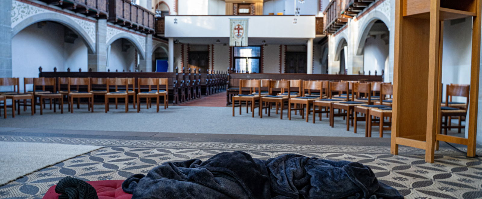 Ein Schlafsack liegt im Altarraum einer Kirche.