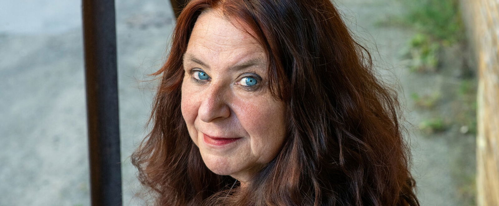 Eine als Frau lesbare Person mit schulterlangen rotbraunen Haaren.