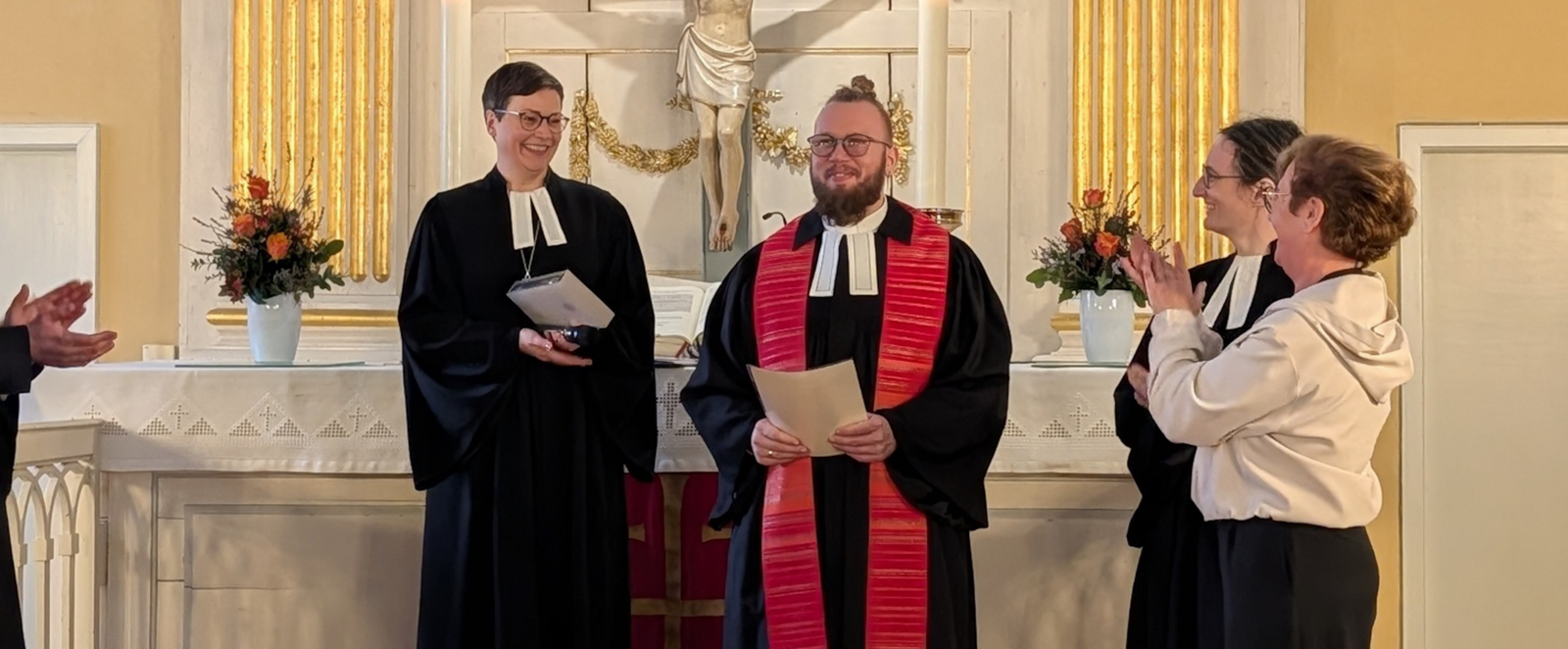 Drei Personen stehen neben einer männlich gelesenen und applaudieren.