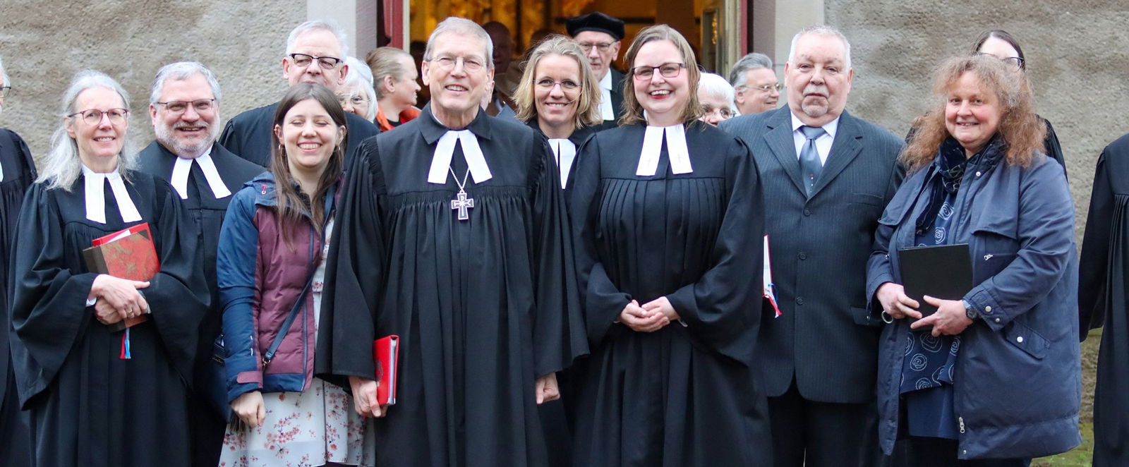 Menschen in Talar und Festkleidung.