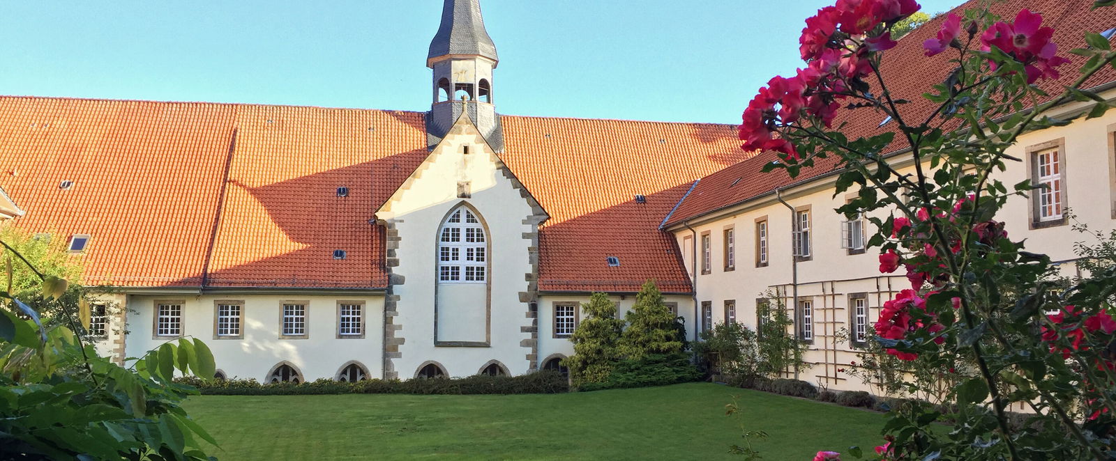 Ein Kloster an grünem Rasen unter blauem Himmel.