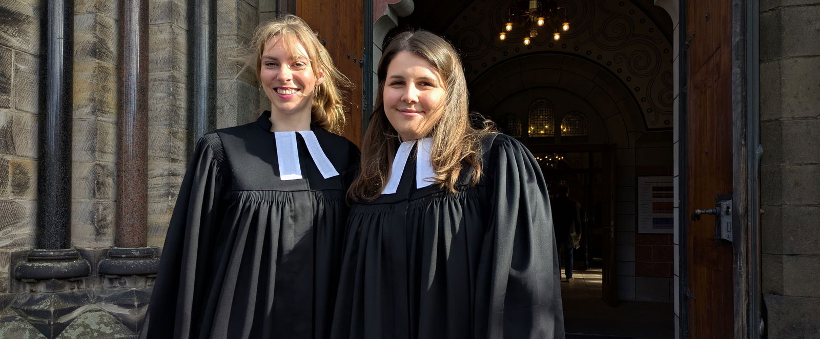 Zwei Frauen im Talar vor einer Kirche.