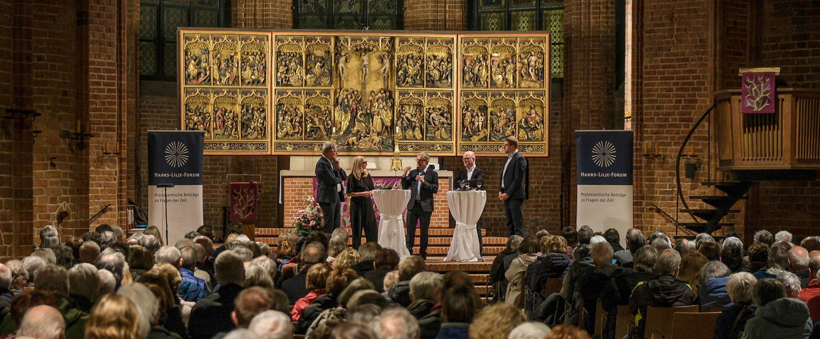 Eine Gruppe von Menschen diskutiert in einer vollen Kirche.