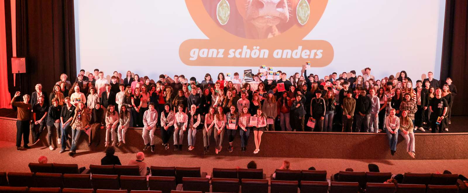 Viele junge Menschen stehen vor einer großen Kinoleinwand.