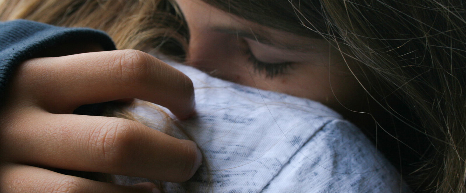 Eine als Frau lesbare Person tröstet ein Kind