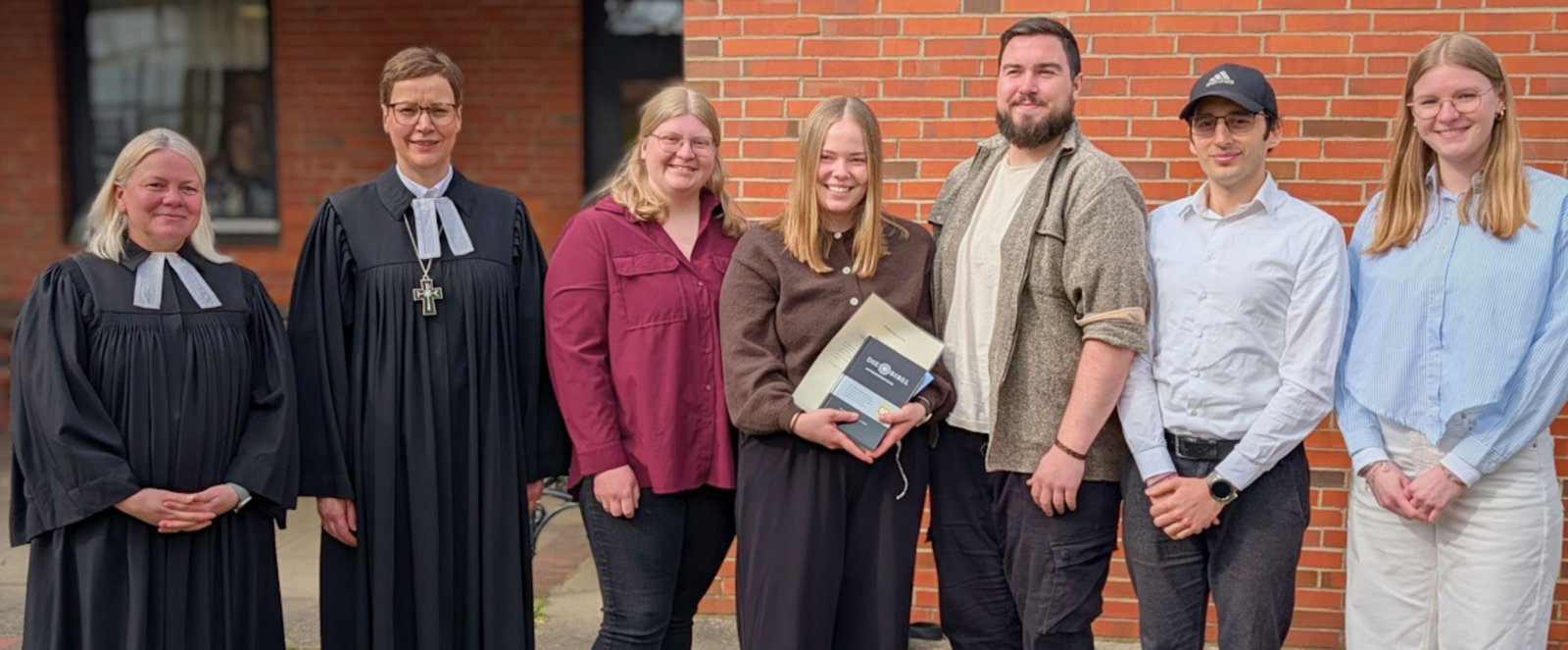 Menschen in Festtagskleidung vor einer Kirche.