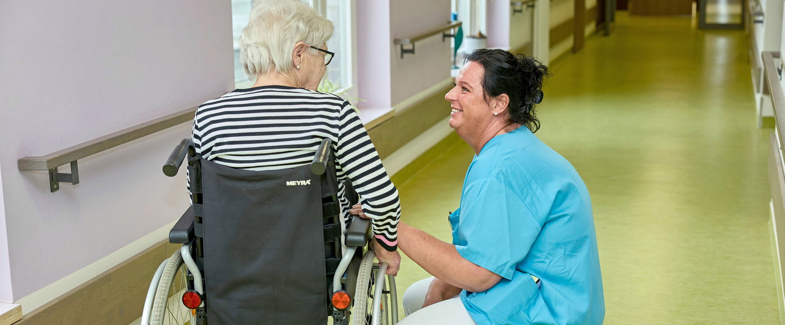 Pflegekraft mit einer Bewohnerin in einem Pflegeheim.