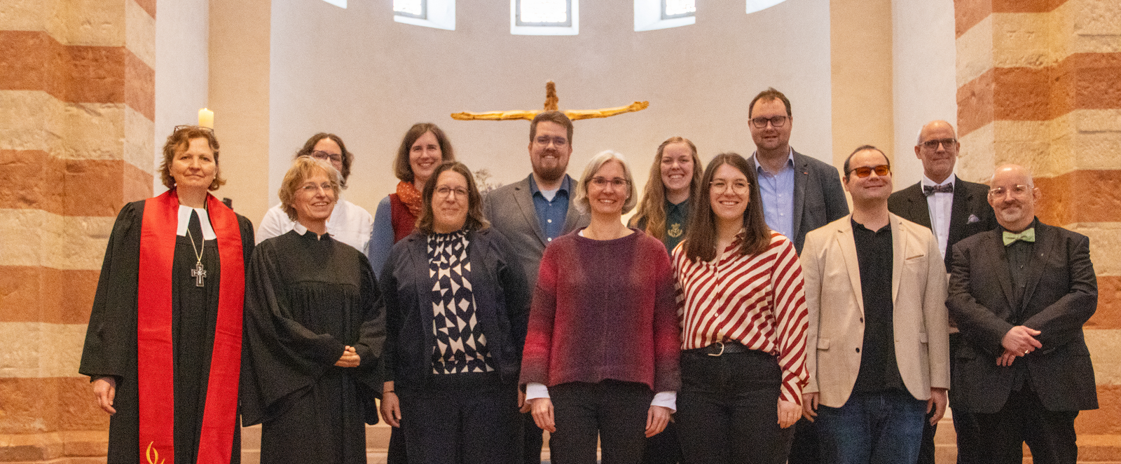 Etwa ein dutzend Menschen stehen zusammen in einer Kirche.
