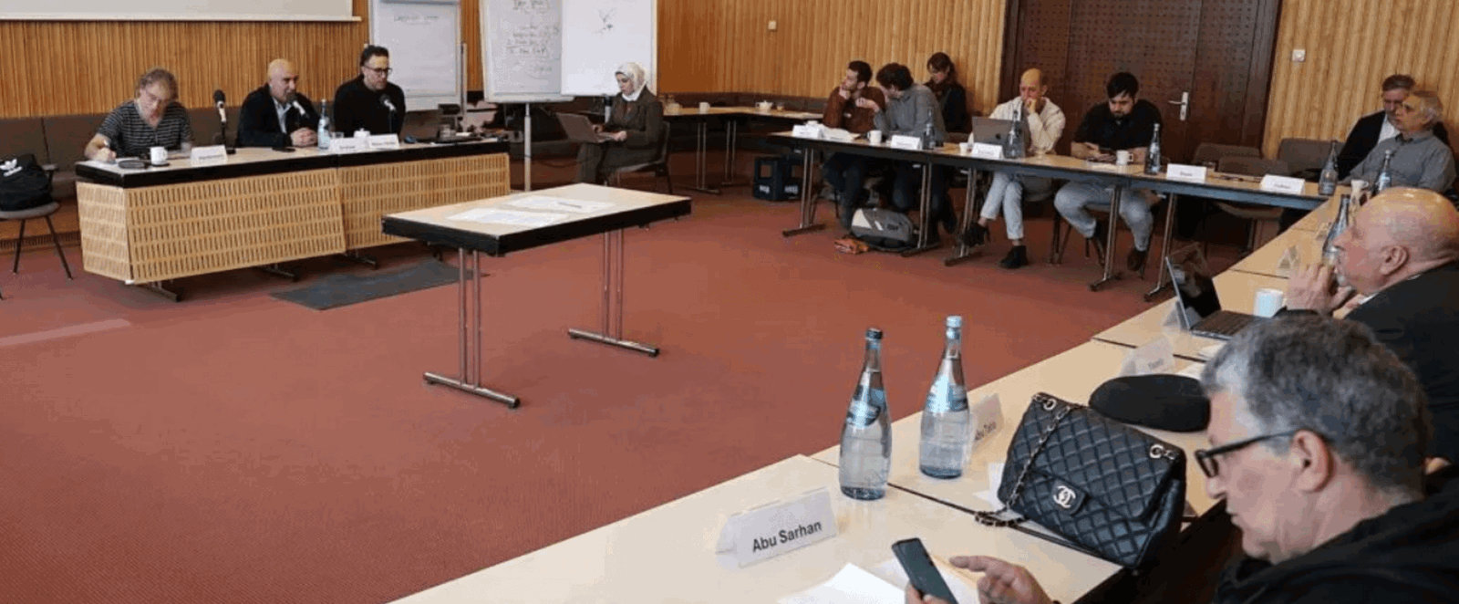 Blick in einen Konferenzraum, in dem etwa ein Dutzend Personen sitzen.