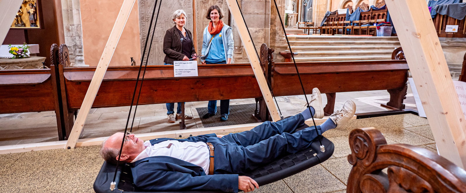 Eine als Mann lesbare Person in einer Schaukel in einer Kirche