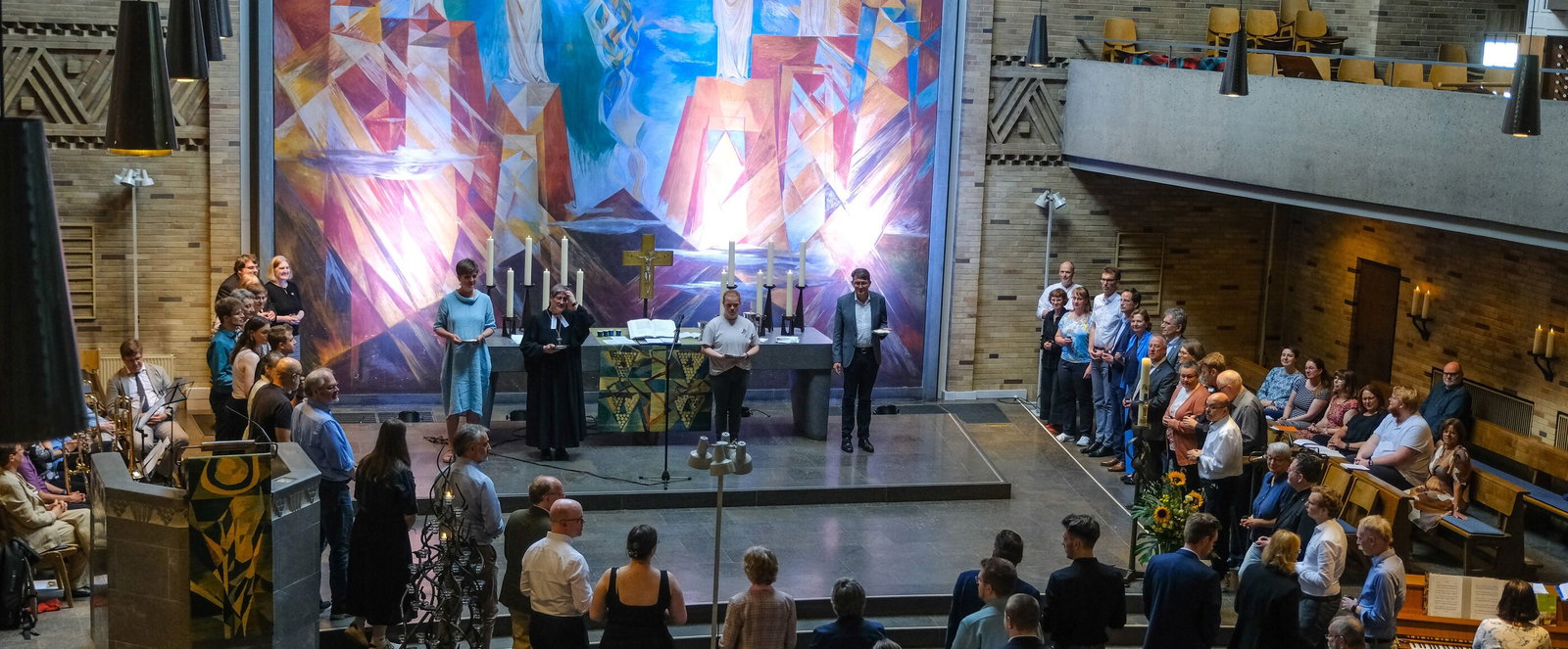 Mehrere Menschen stehen in einer Kirche und feiern Abendmahl.