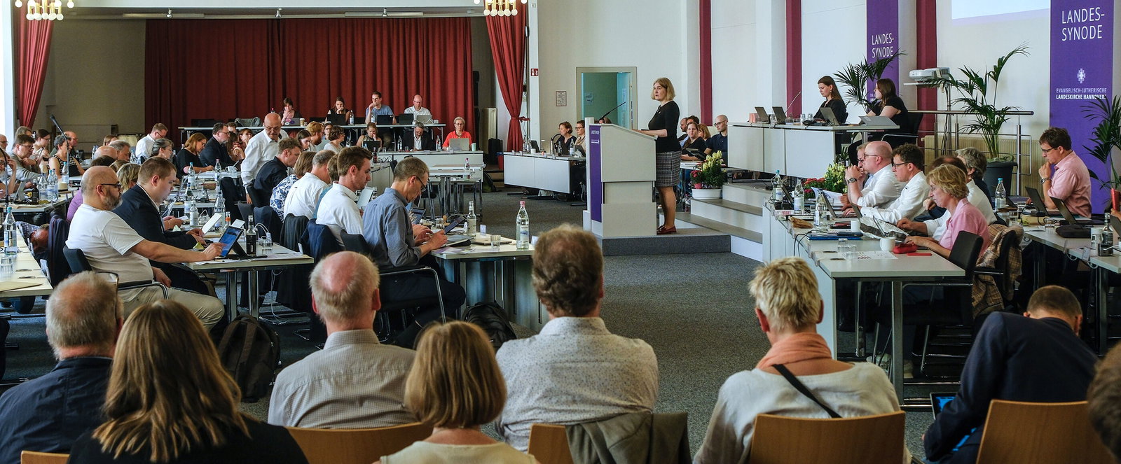 Mehrere Menschen in einem großen Sitzungssaal