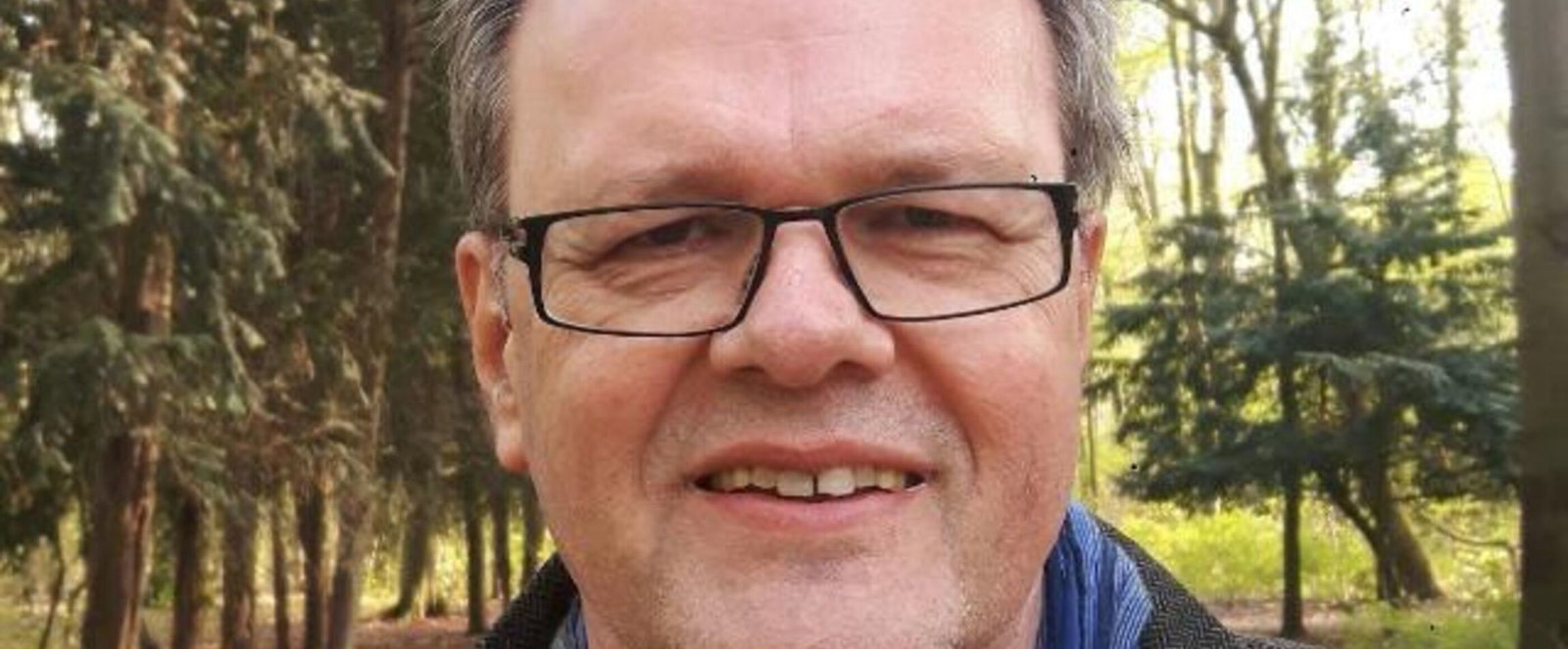 Eine als Mann lesbare Person mit Brille, hoher Stirn und kurzen Haaren.
