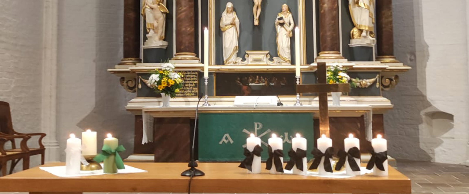 Ein Tisch mit mehreren Kerzen mit Trauerflor vor einem Altar
