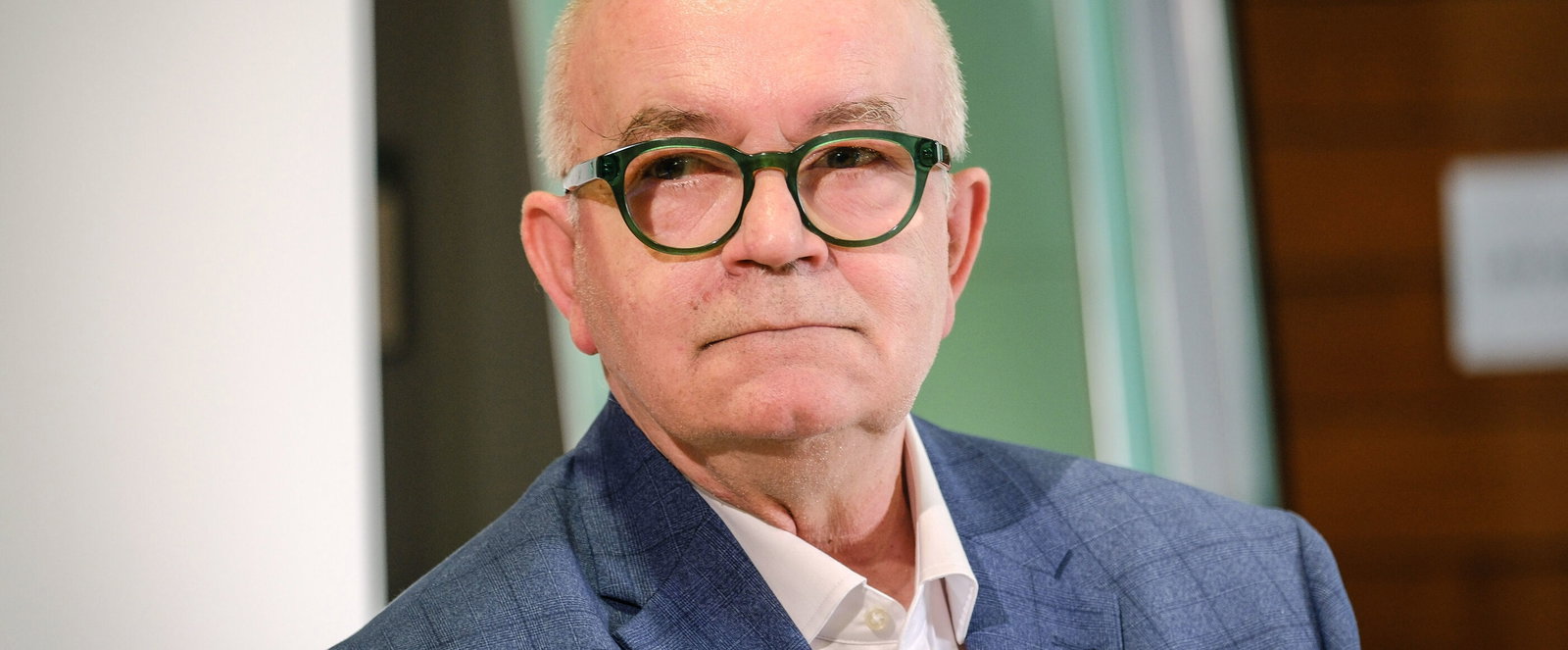 Eine als Mann lesbare Person mit Glatze und markanter Brille.