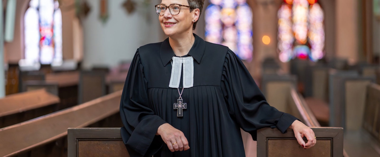 Eine als Frau lesbare Person im Talar in einer Kirche.