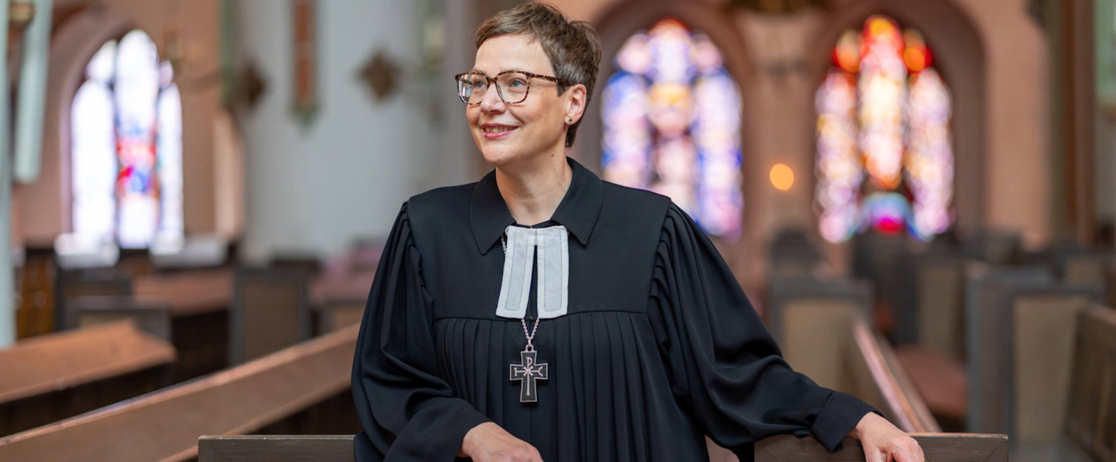 Eine als Frau lesbare Person im Talar in einer Kirche.