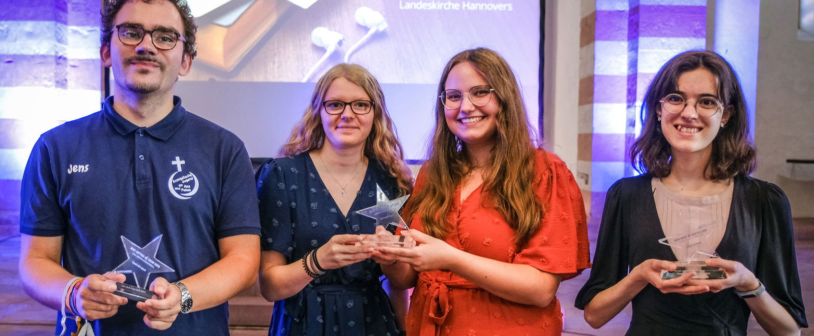 Vier junge Menschen posieren bei einer Preisverleihung mit einem Pokal.