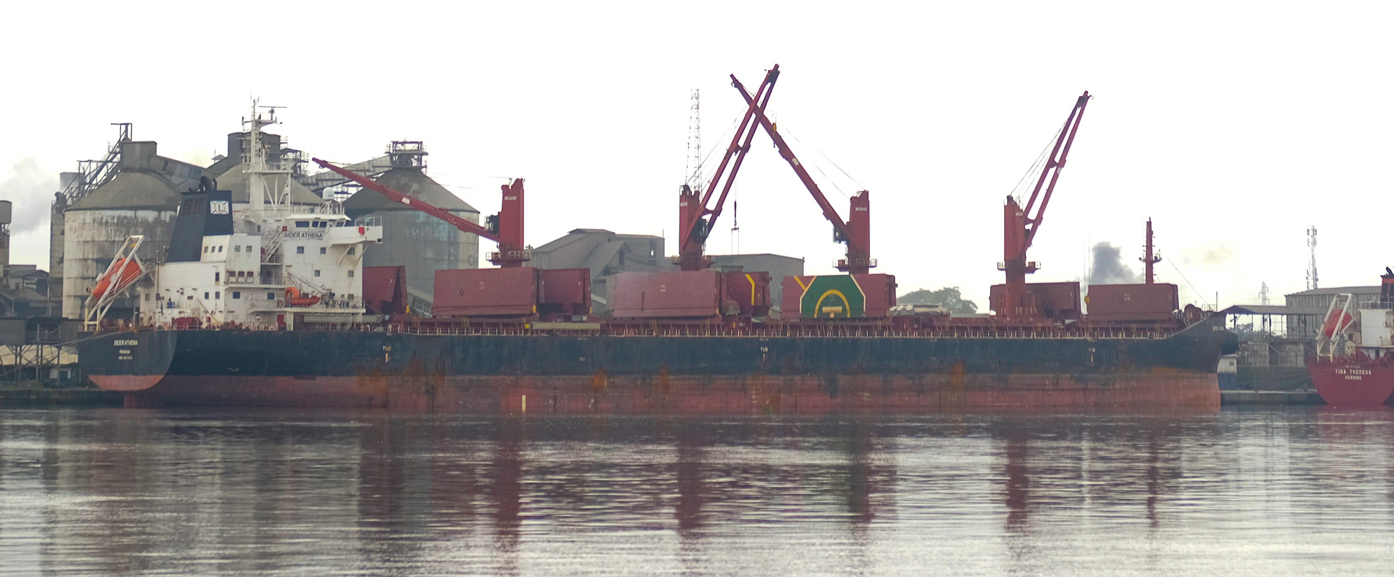 Ein Hafen mit Kränen und Gebäuden an grauem Wasser und grauem Himmel.