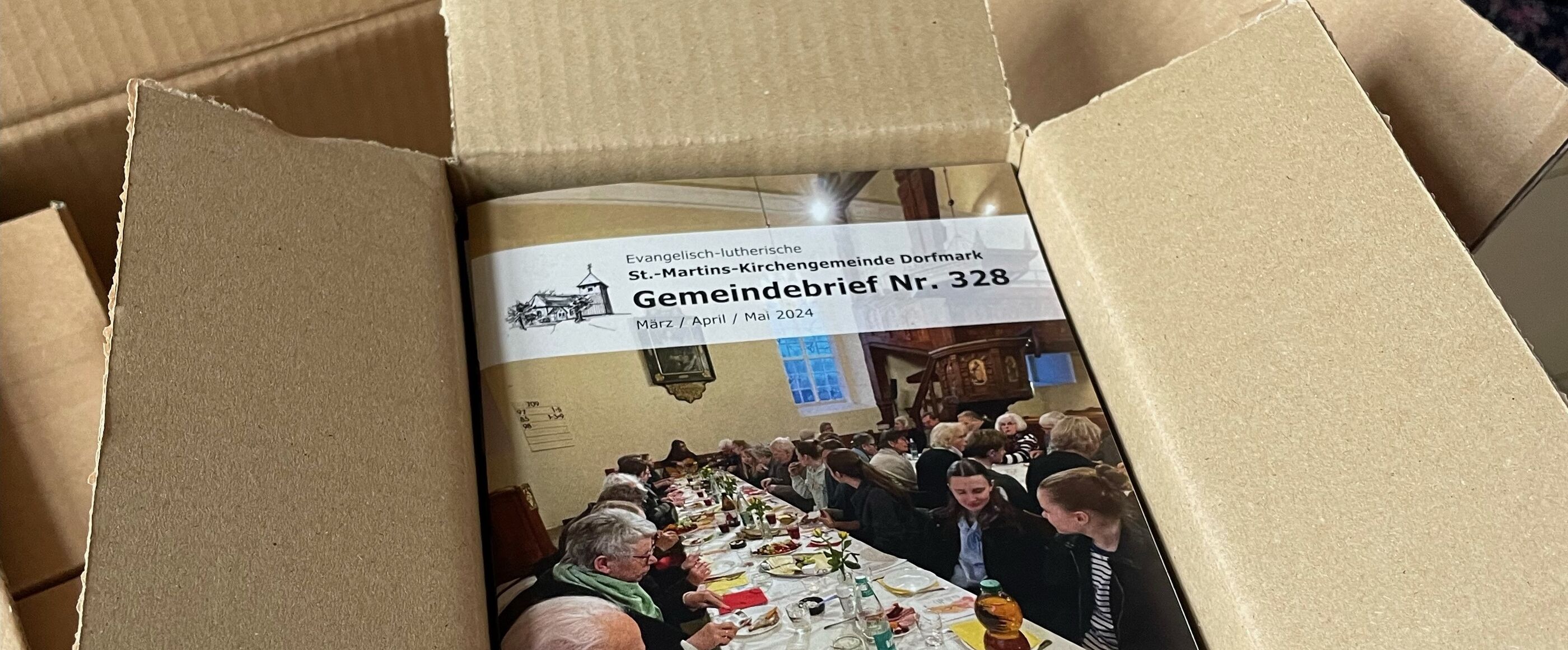 In einem geöffneten Karton liegen Broschüren.