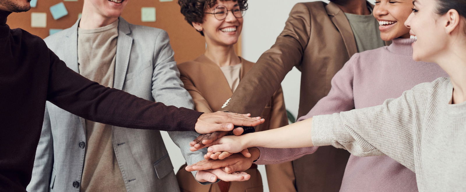 Mehrere Personen unterschiedlicher Hautfarben legen ihre Hände aufeinander.