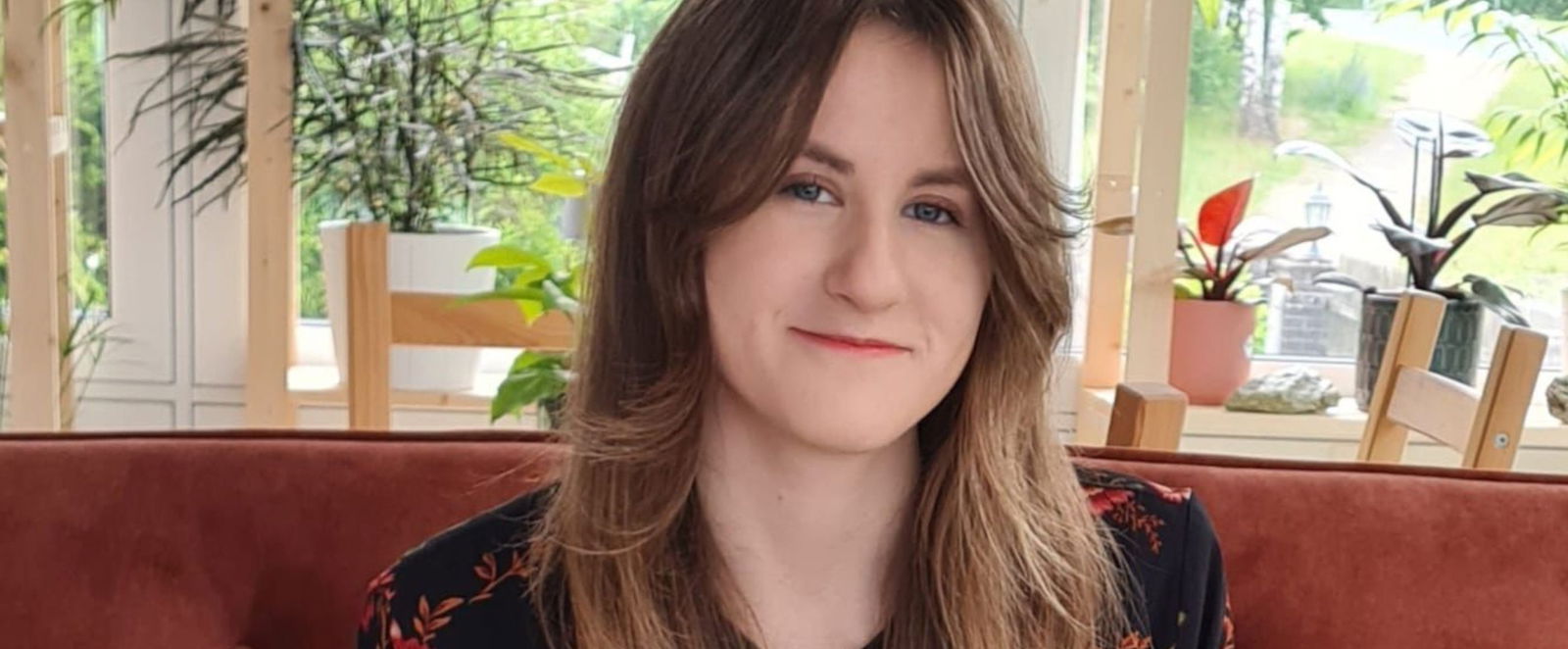 Ein junges Mädchen mit langen Haaren sitzt auf einer roten Couch