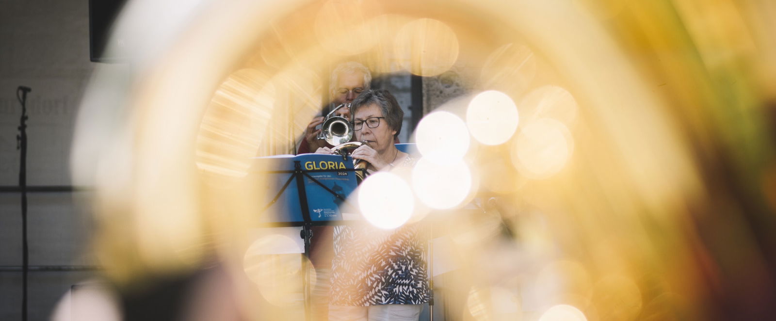 Ein Posaunenchor, aufgenommen durch ein Instrument, das unscharf im Vordergrund steht.