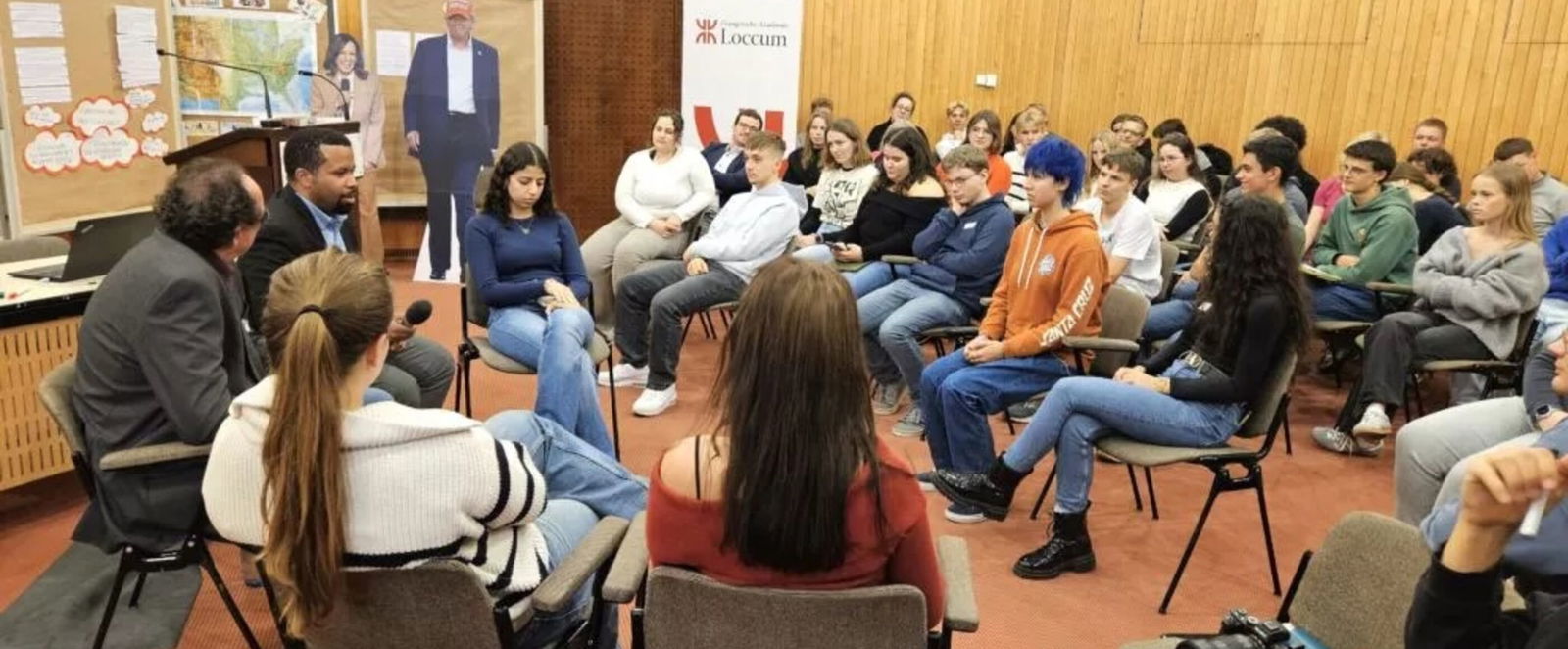 Mehrere junge Menschen sitzen in einem Raum auf Stühlen.