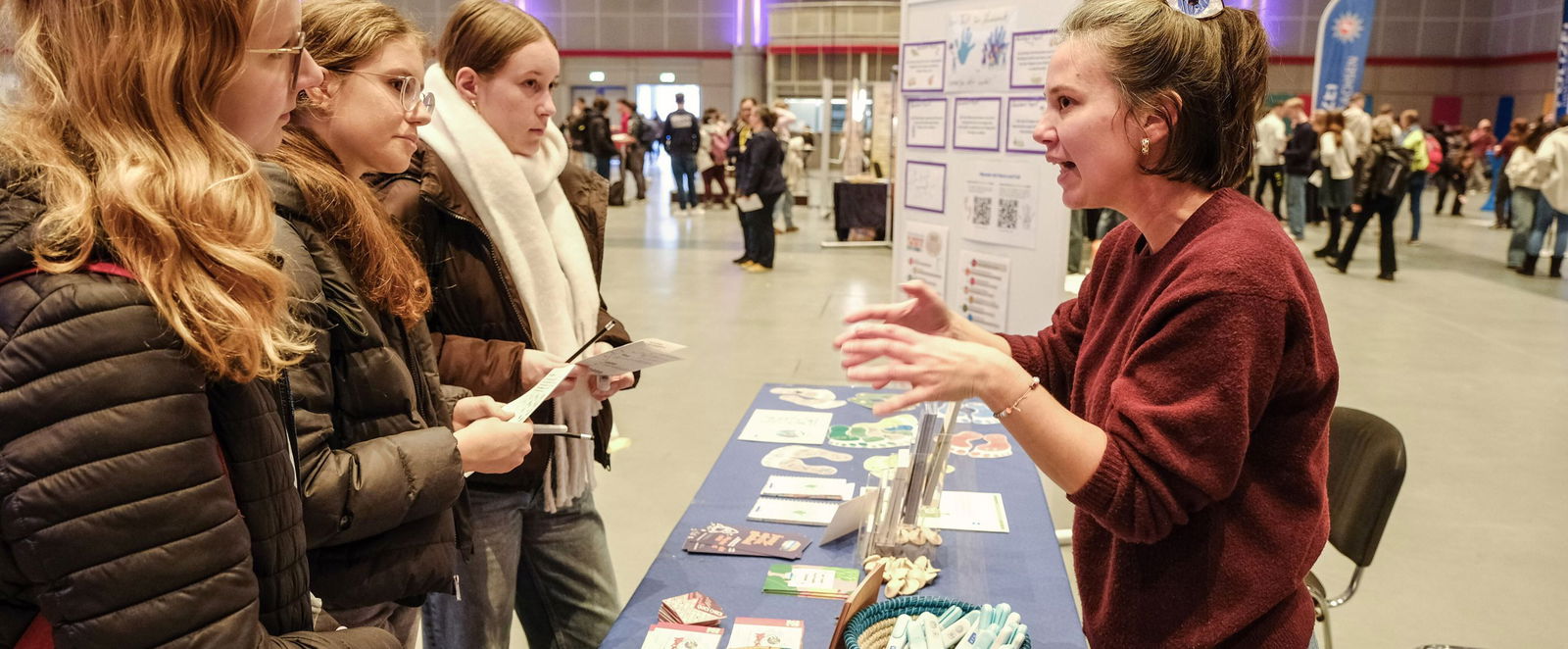eine Frau spricht auf einer Bühne zu mehreren Menschen