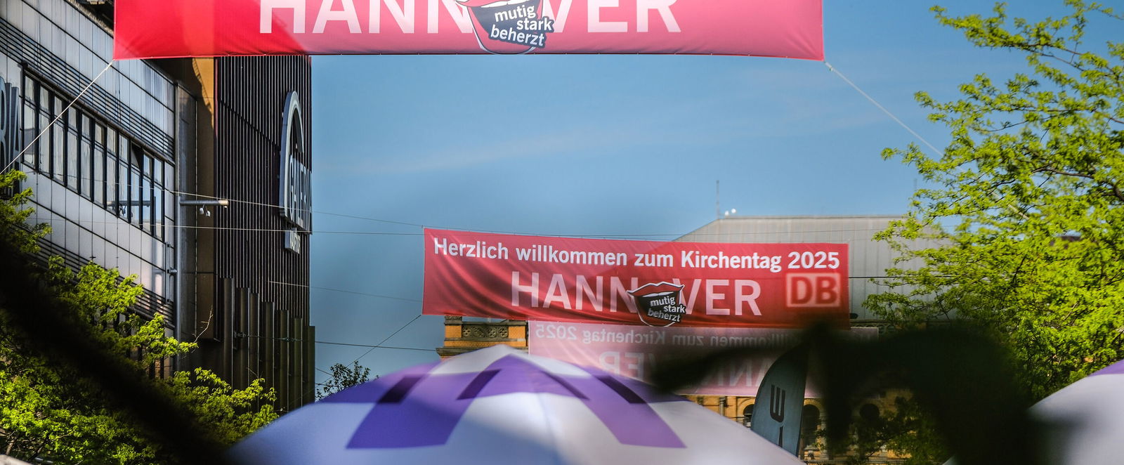 Ein Banner mit dem Kirchentagsschriftzug hängt über einer Straße.