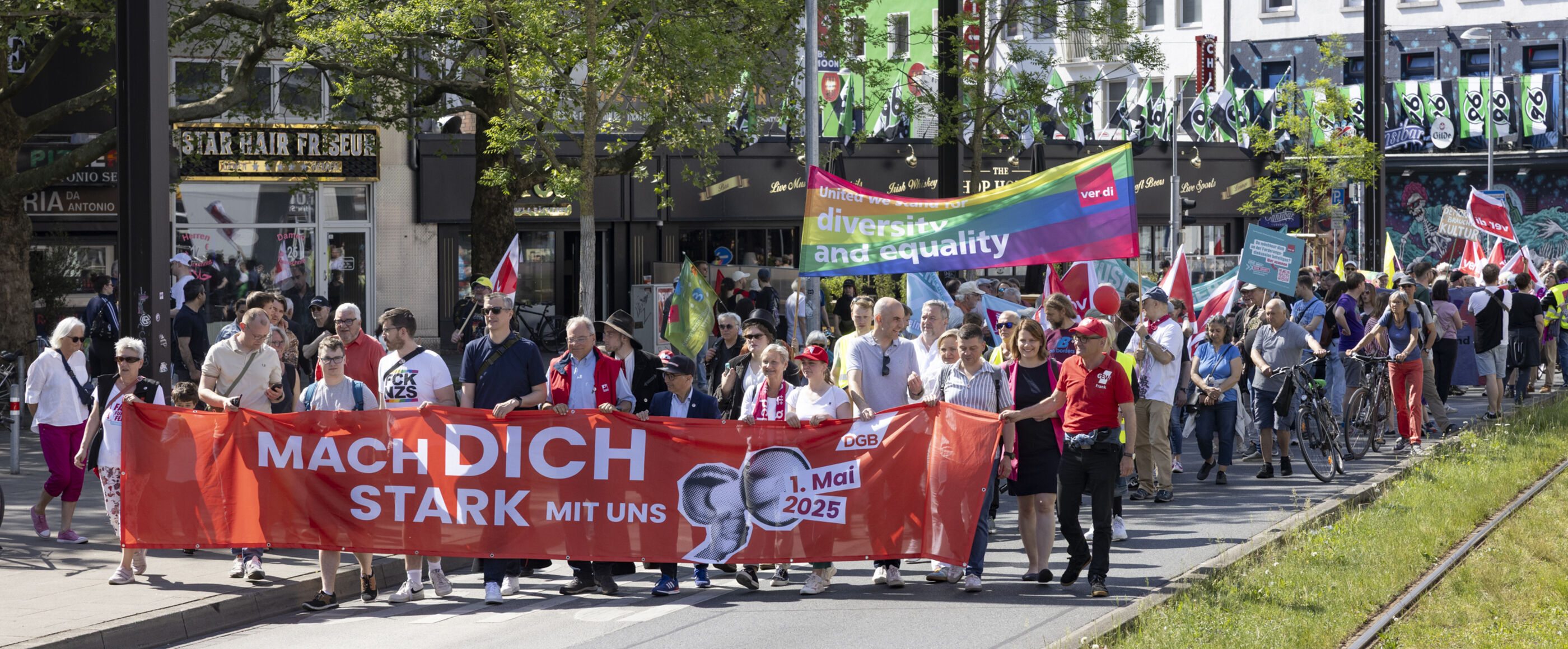 Ein Demonstrationszug mit vielen Menschen und Plakaten auf der Straße.