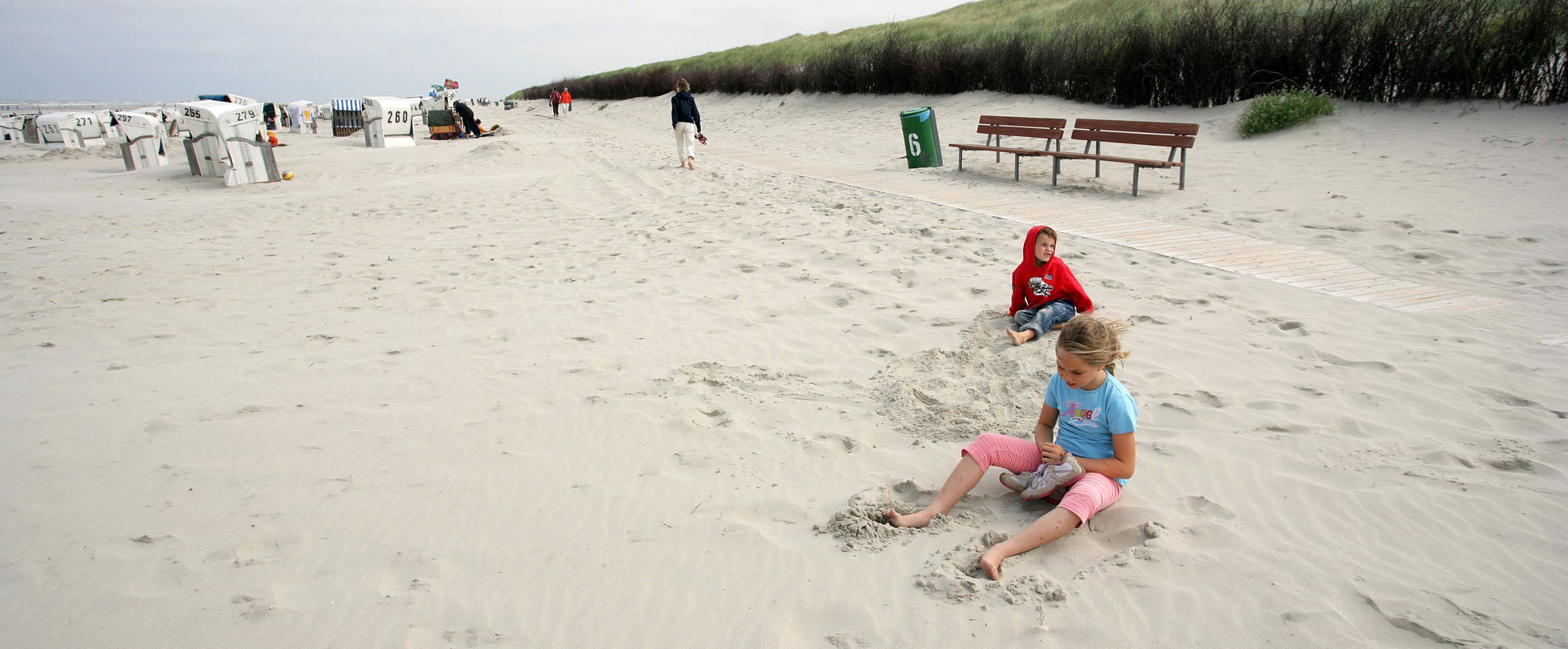 Zwei Kinder spielen im Sand am Meer.