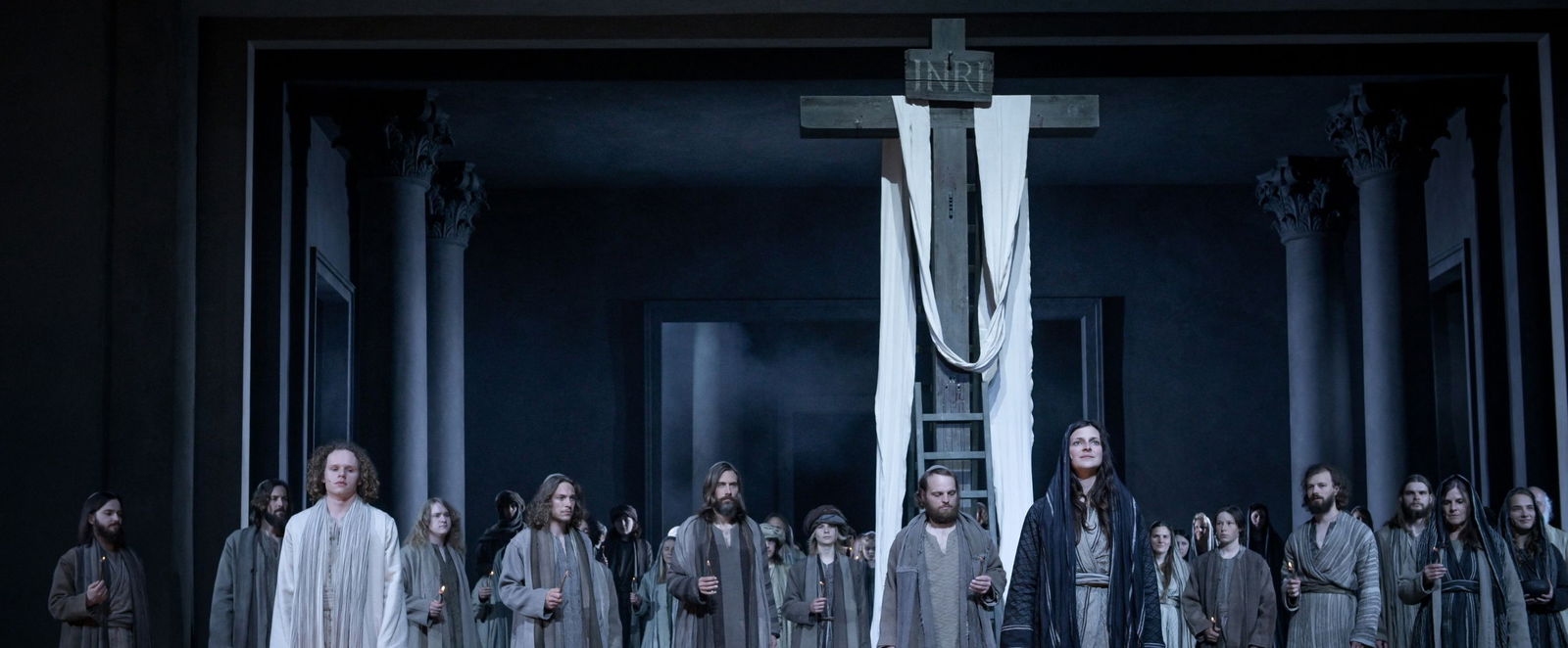 Menschen in Kostümen vor einem Kreuz.