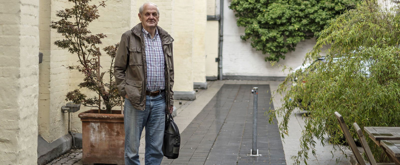 Eine als Mann lesbare Person im Innenhof eines Hotels.