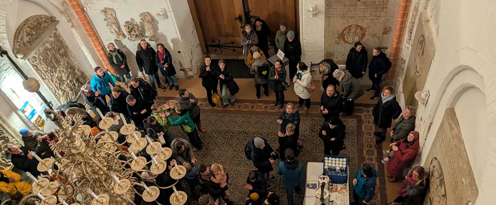 Blick von oben in einen Turm, in dem Menschen stehen und Kaffee auf Tischen ausgeschenkt wird.