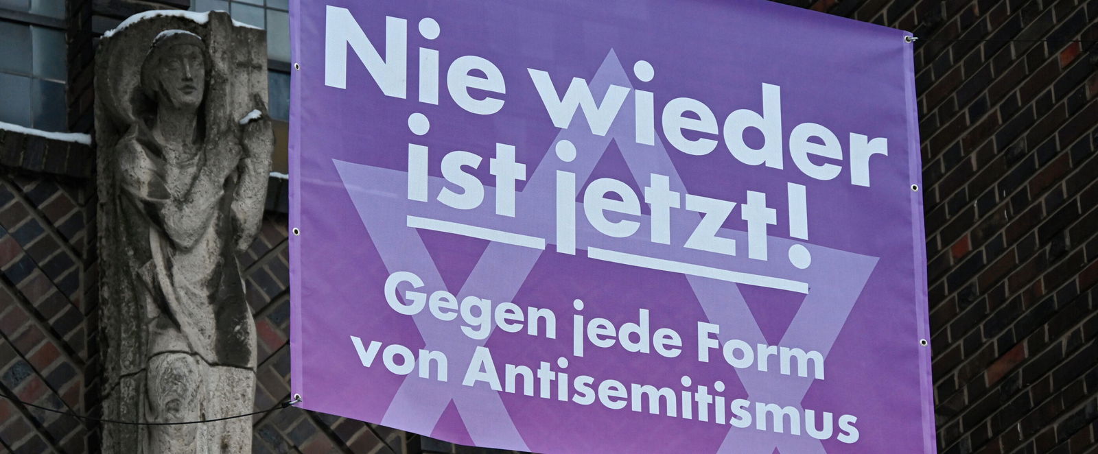 Banner mit der Aufschrift "Nie wieder ist jetzt! Gegen jede Form von Antisemitismus" an einer Kirche