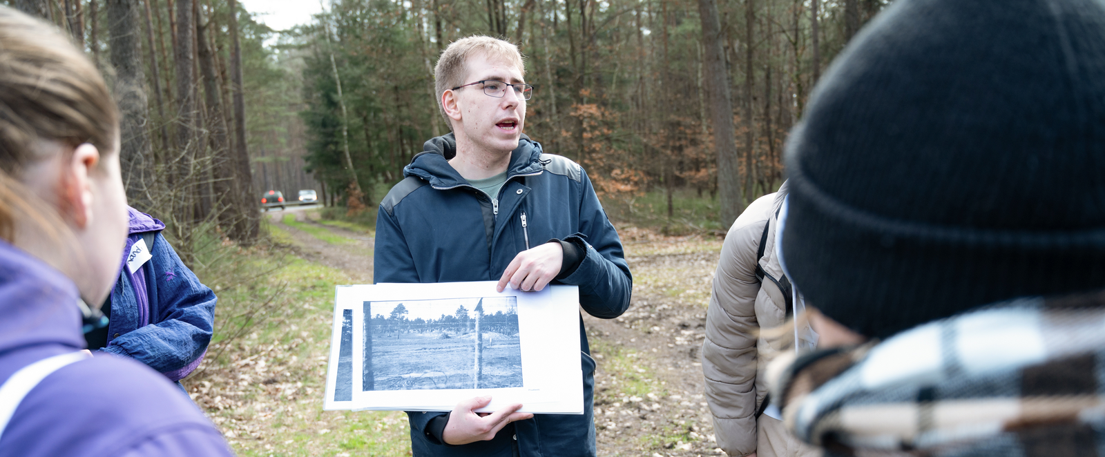 Mehrere junge Menschen stehen um eine Person, die ein schwarz-weißes Foto zeigt.
