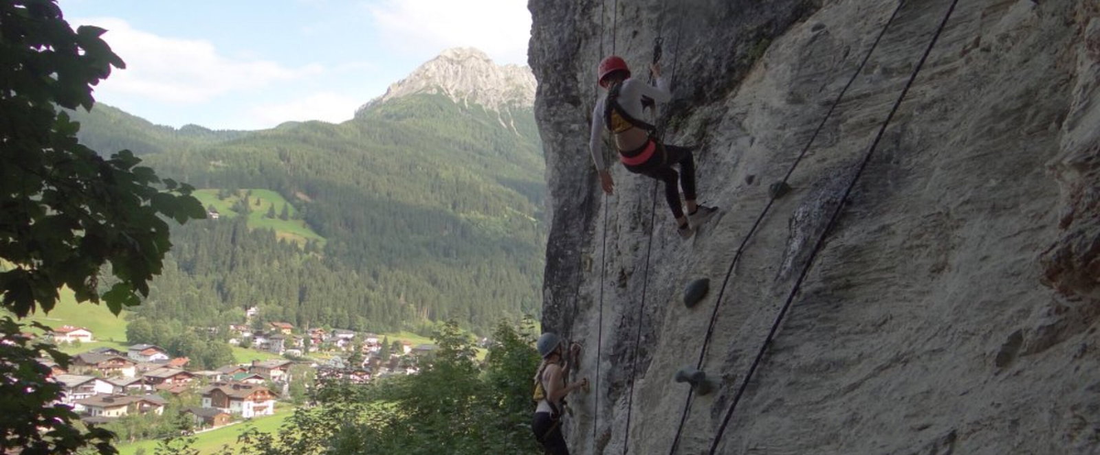 Eine Person klettert an einem rauen Felsen.