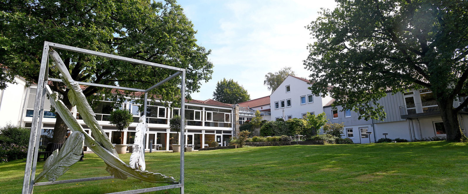 Ein Tagungshaus mit einer Wiese und einem Kunstwerk im Vordergrund.