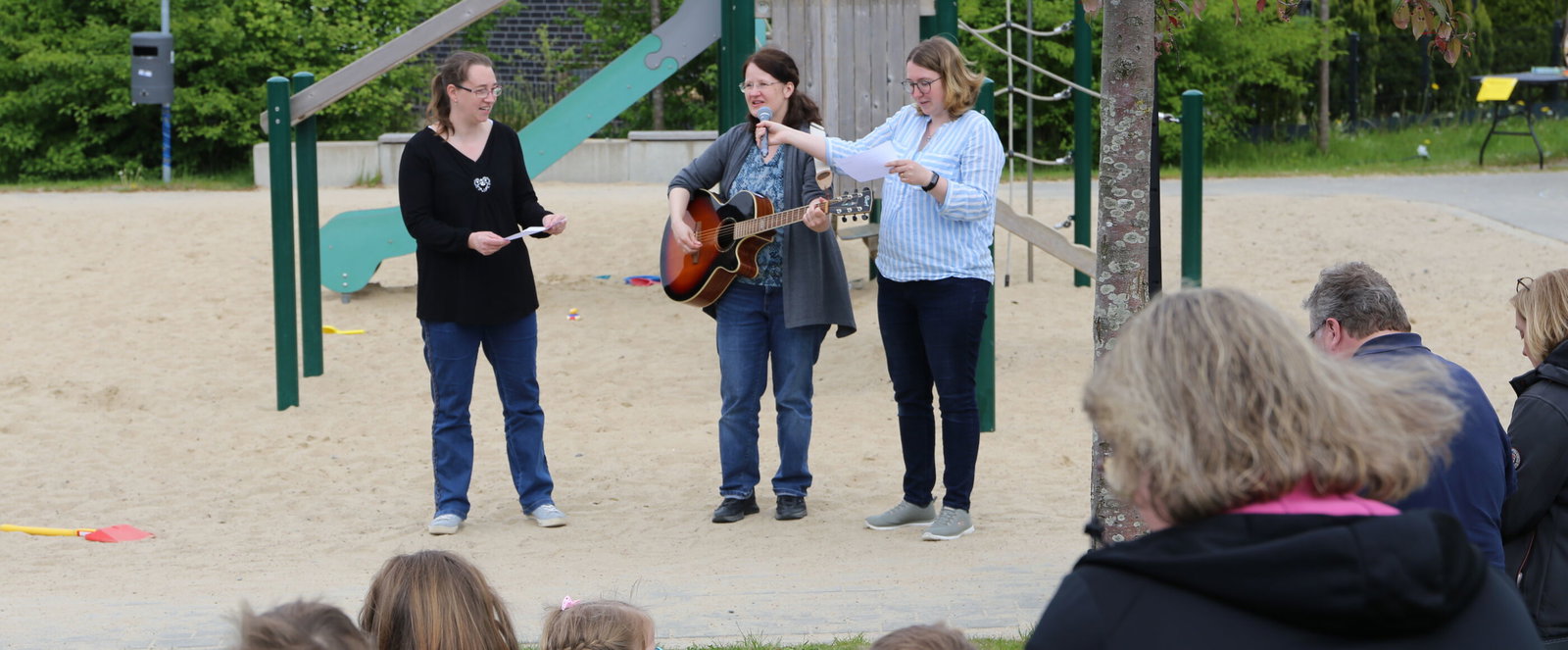 Menschen musizieren auf einem Spielplatz.