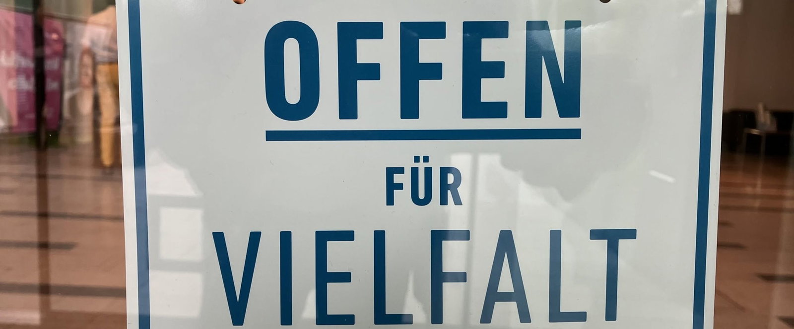 Das Bild zeigt ein Schild an einer Ladentür. Es trägt den Schriftzug "Offen für Vielfalt"