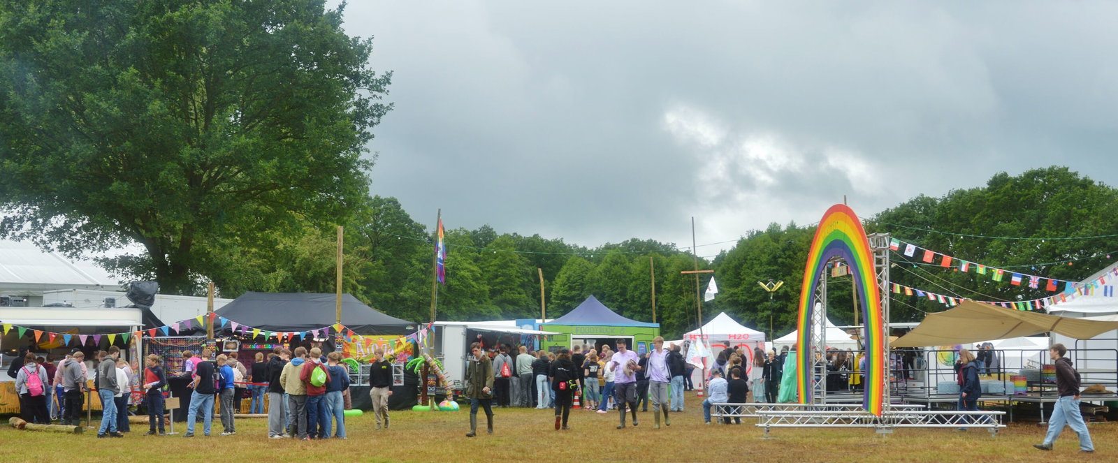 Eine Zeltstadt mit vielen jungen Menschen und einem großen Regenbogen.