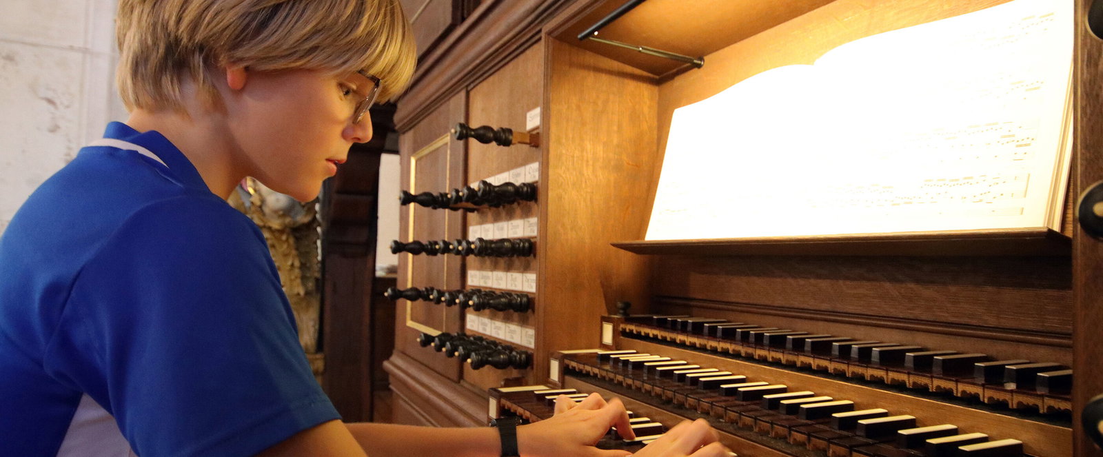 Eine als Junge lesbare Person spielt auf einer Orgel.