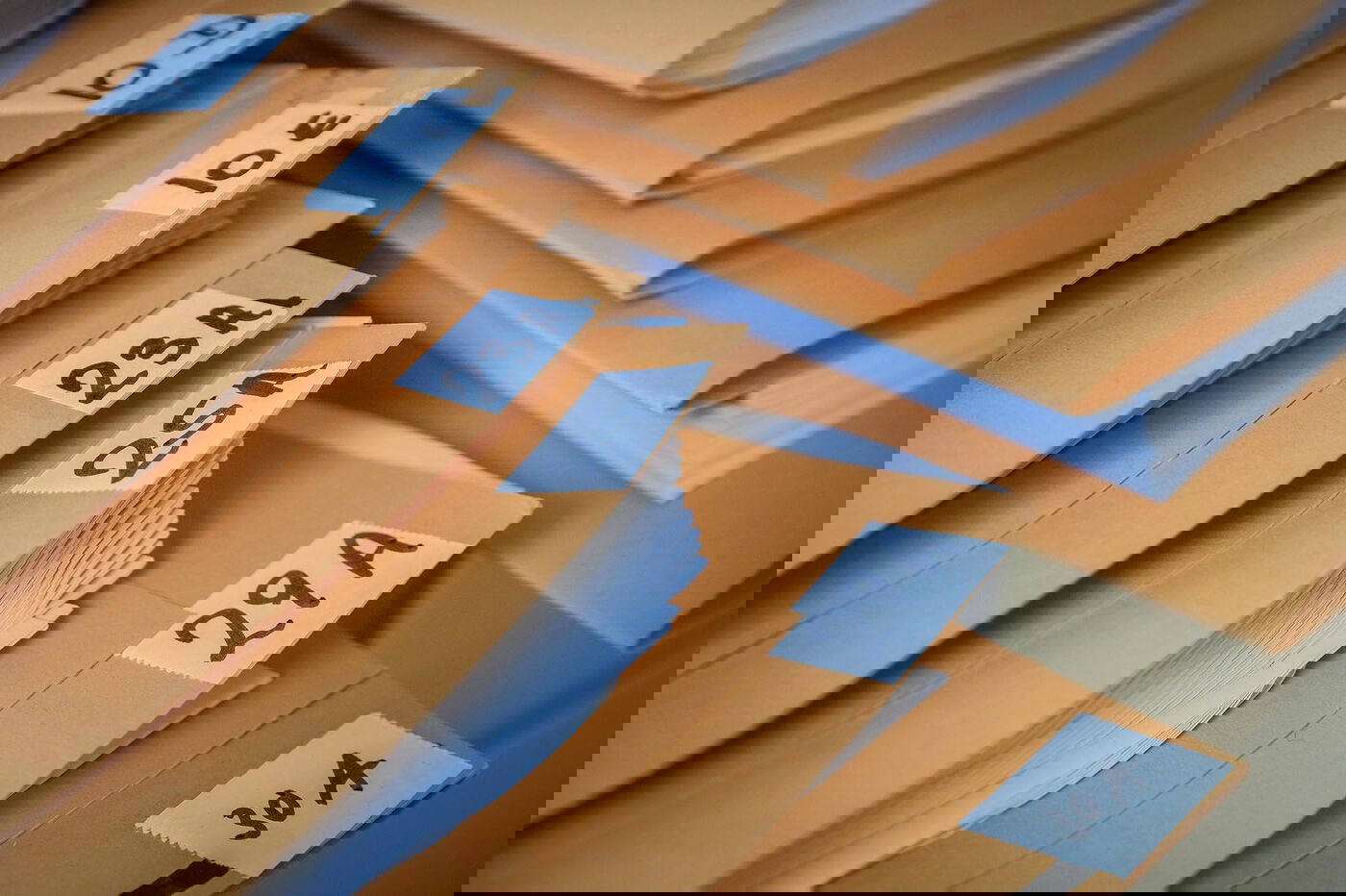 Das Bild zeigt einen Stapel von Papp-Mappen, die übereinander liegen. 