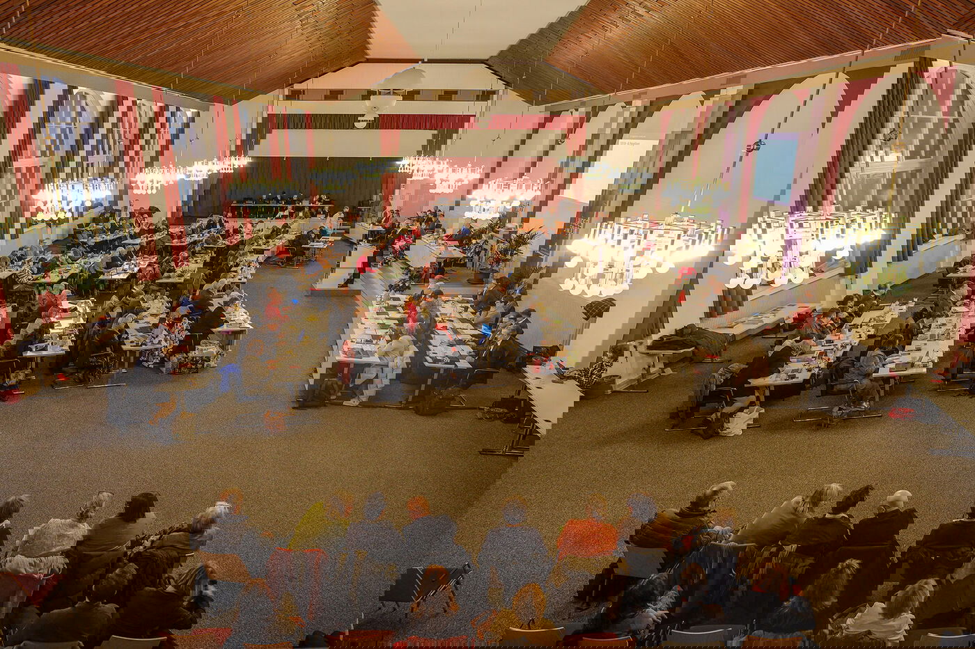 Weiblich und männlich zu lesende Personen sitzen im Tagungsraum der Landessynode an Tischen. Am Pult steht eine männlich zu lesende Person.