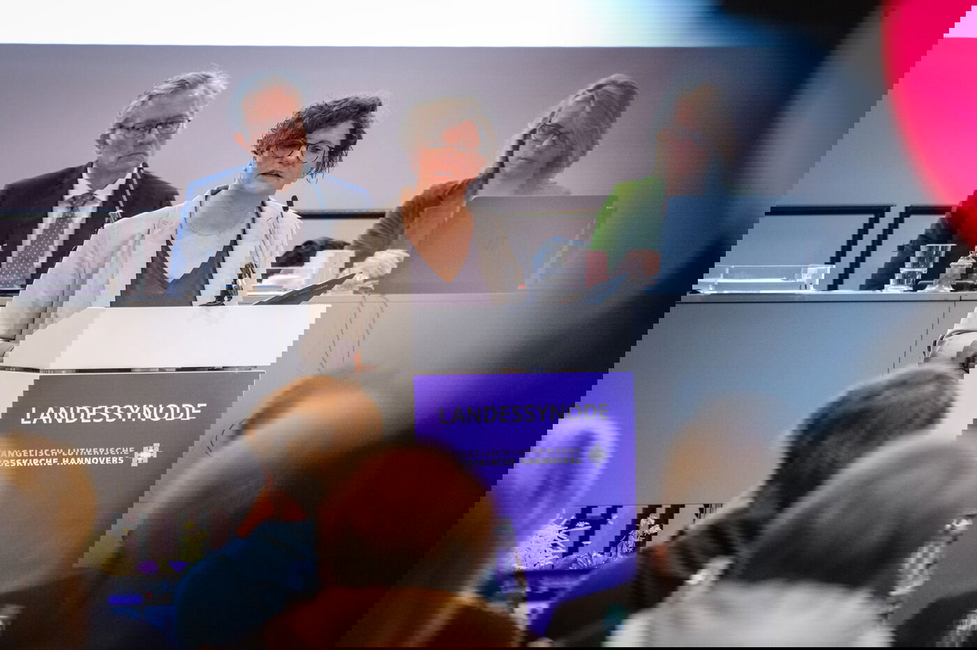 Eine weiblich lesbare Person hält an einem Podium einen Vortrag.