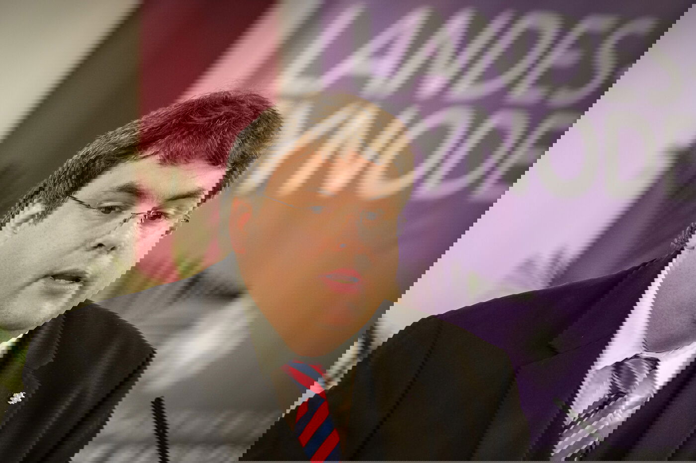 Eine männlich lesbare Person an einem Rednerpult