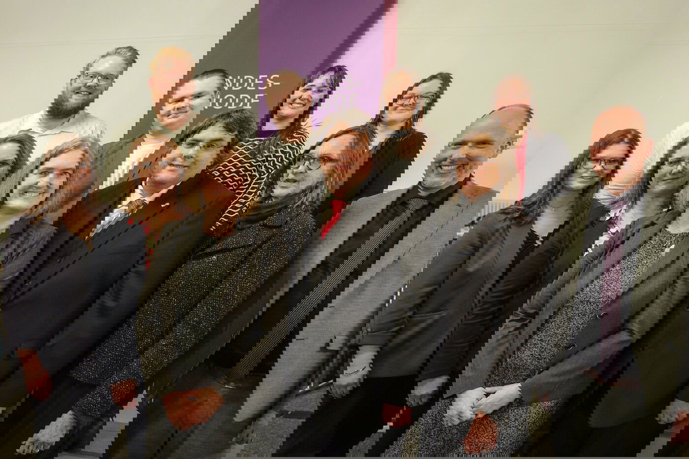 Sechs weiblich und vier männlich zu lesende Personen stehen als Gruppe zusammen und schauen in die Kamera.